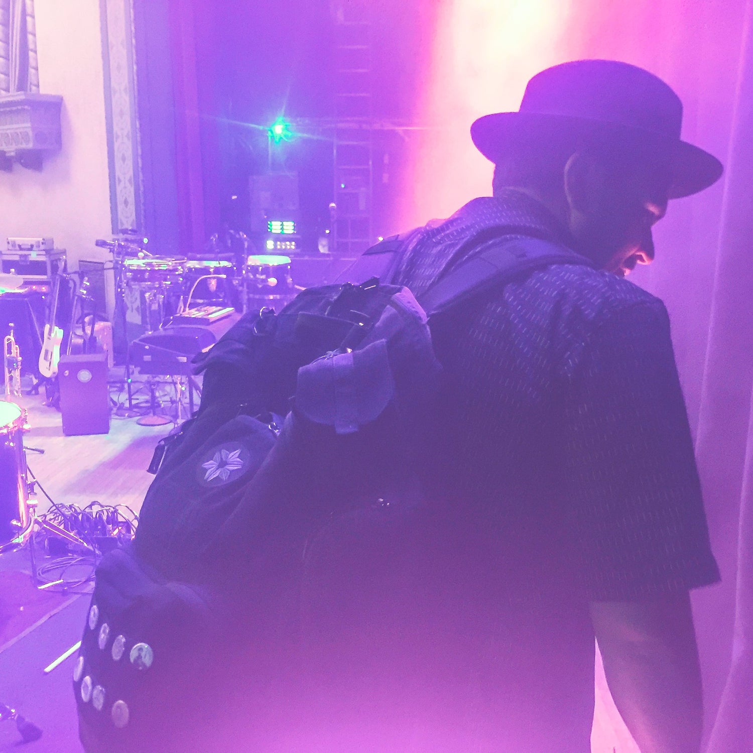 Person with a backpack on a stage with purple lighting