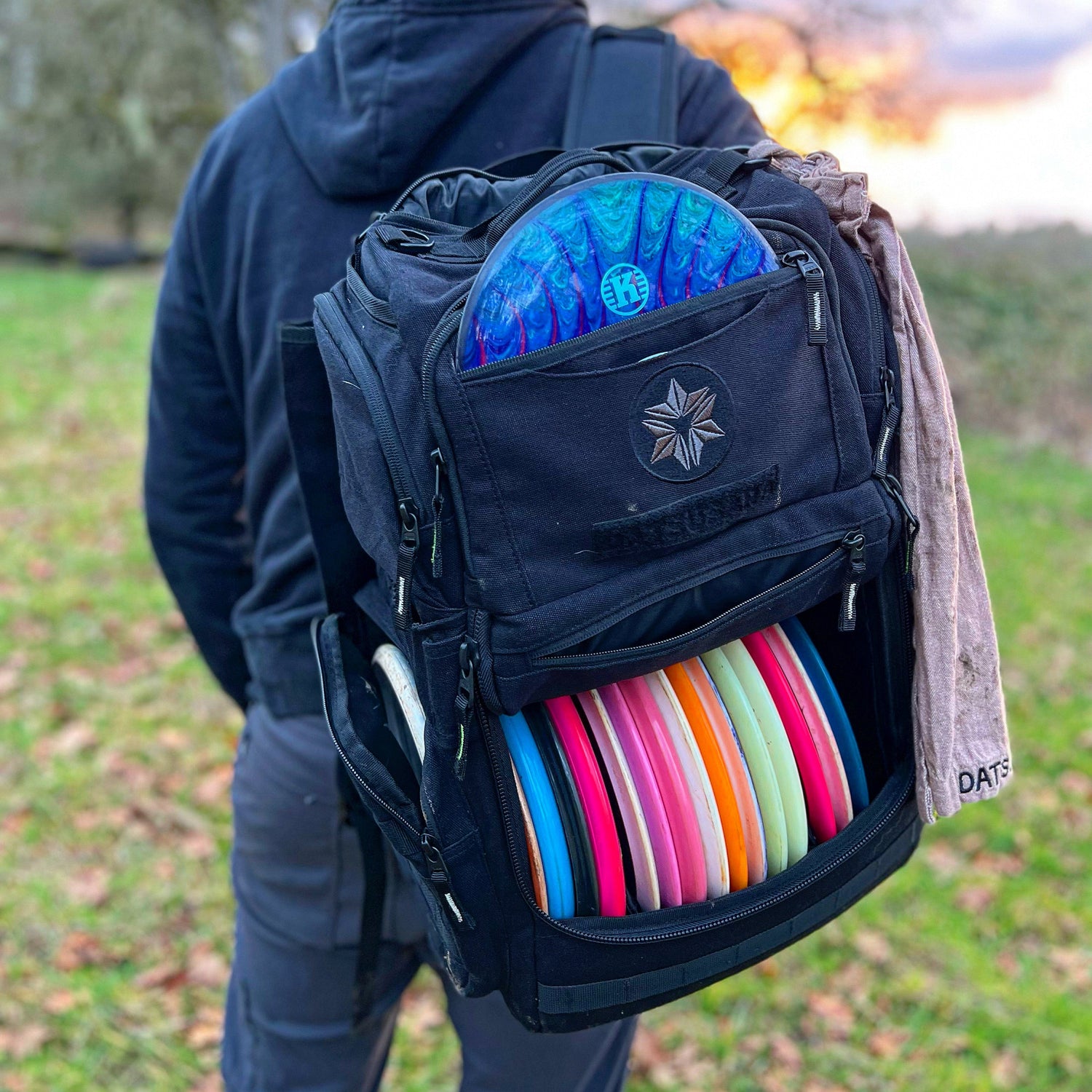Person with a backpack full of colorful discs in an outdoor setting